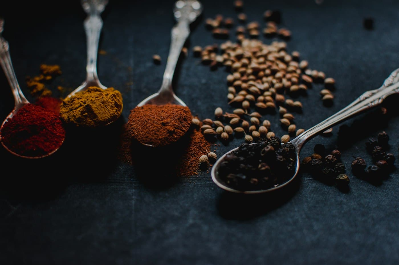 Spoons of ground spice and whole peppercorns